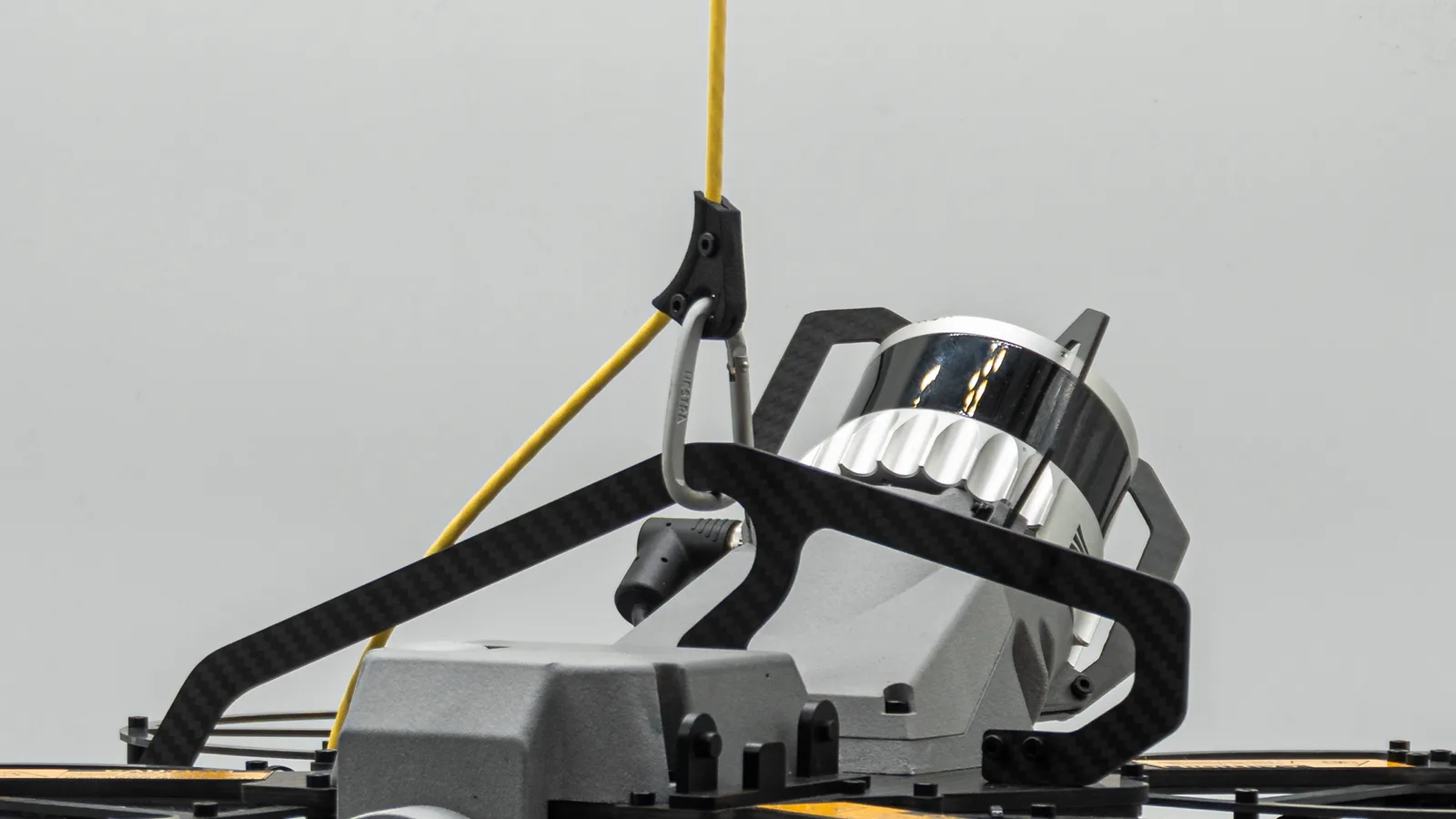 Close-up of the Scout 137 Gen 3 Tether Deployment System — the yellow tether clipped by carabiner to the drone's carbon-fibre frame above the LiDAR