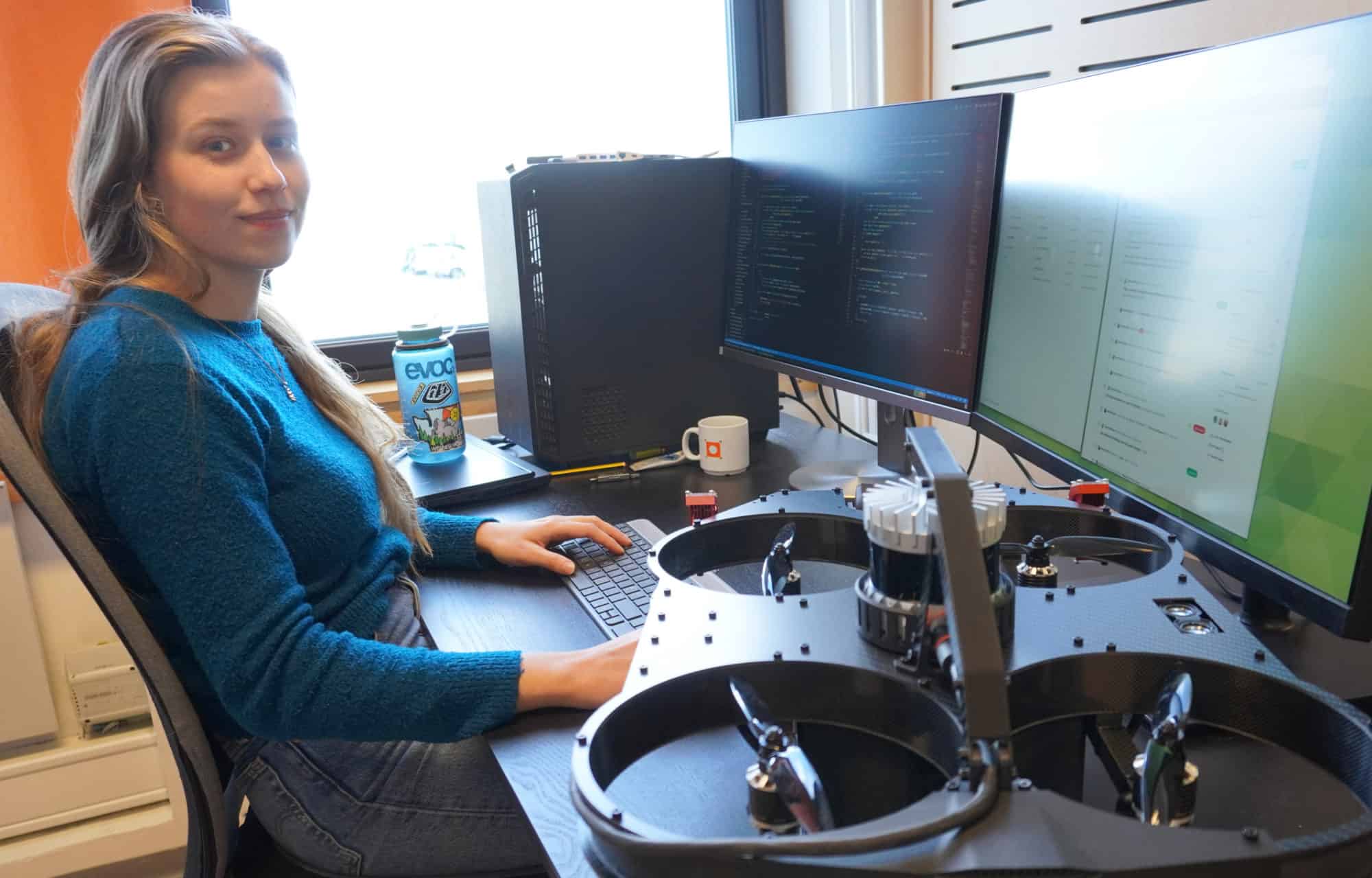 Young woman sitting at desk with computer and UAV