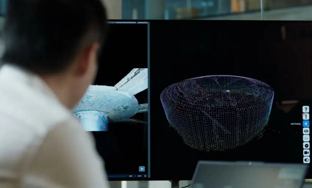 Man sitting in front of computer screen with 3D point cloud map on it